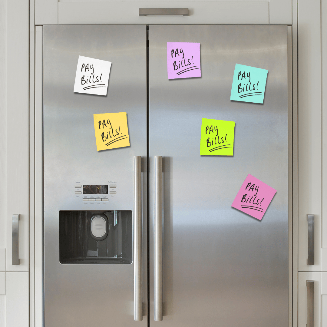 A stainless steel refrigerator with six colourful sticky notes on the doors, each reading “Pay Bills!” in black marker. The notes are pink, yellow, blue, and green. The refrigerator has a water and ice dispenser.
